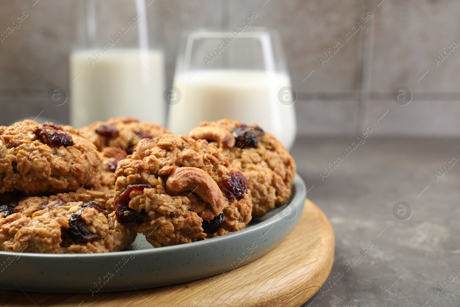 Photo of Delicious oatmeal cookies with raisins and nuts on grey table, closeup. Space for text