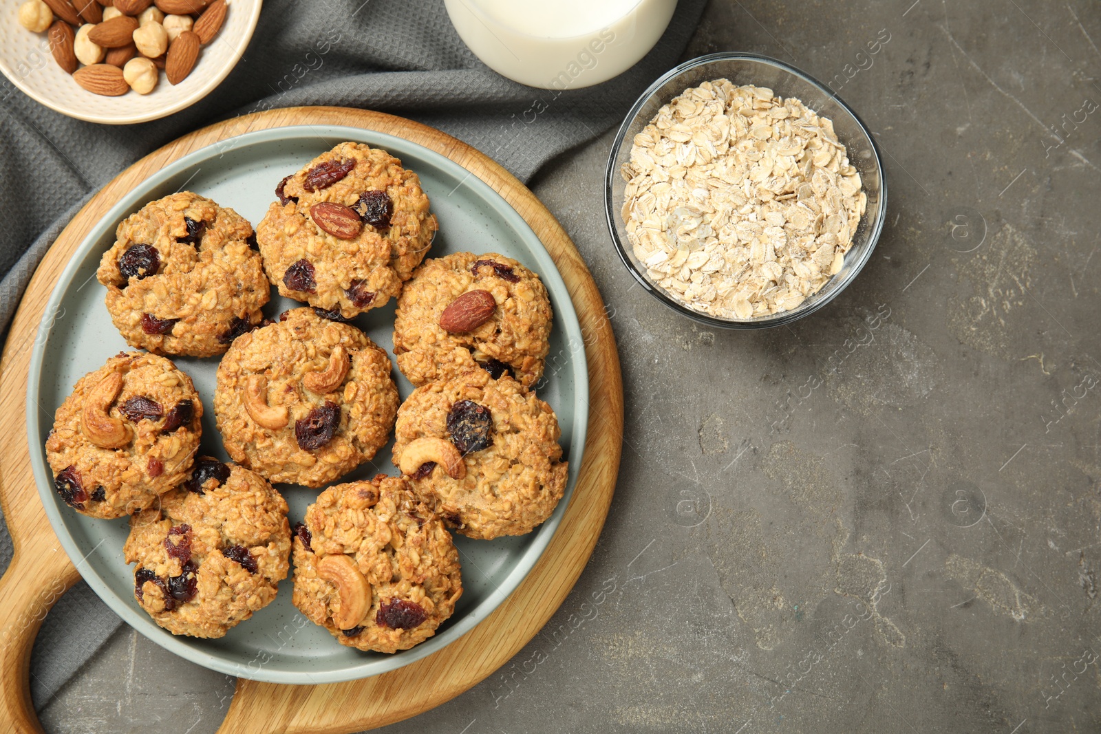 Photo of Delicious oatmeal cookies with raisins and nuts on grey table, flat lay. Space for text