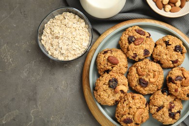 Photo of Delicious oatmeal cookies with raisins and nuts on grey table, flat lay. Space for text