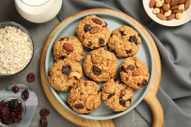 Delicious oatmeal cookies with raisins and nuts on grey table, flat lay