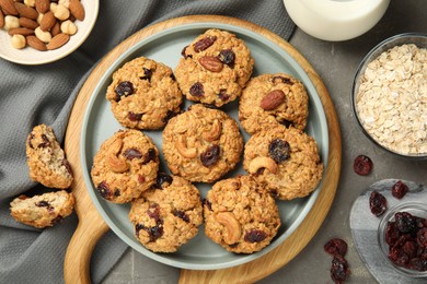 Delicious oatmeal cookies with raisins and nuts on grey table, flat lay