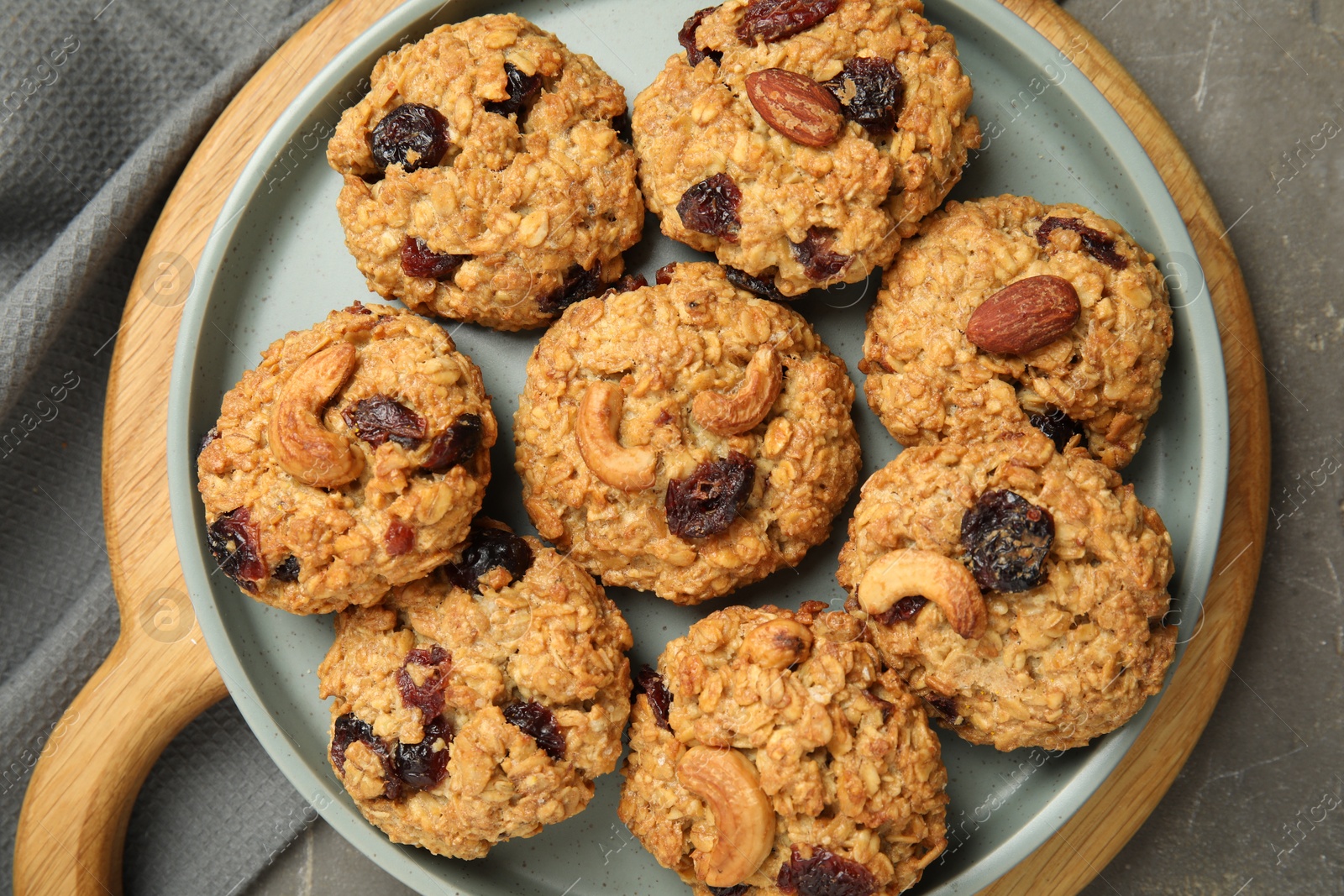 Photo of Delicious oatmeal cookies with raisins and nuts on grey table, top view