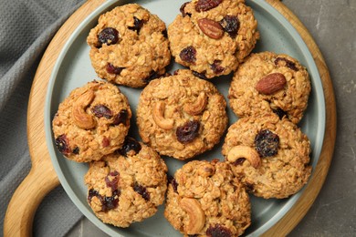 Photo of Delicious oatmeal cookies with raisins and nuts on grey table, top view