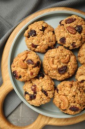 Delicious oatmeal cookies with raisins and nuts on grey table, top view