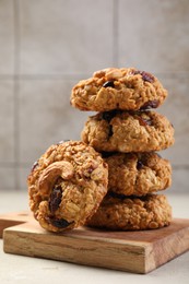 Delicious oatmeal cookies with raisins and nuts on light grey table