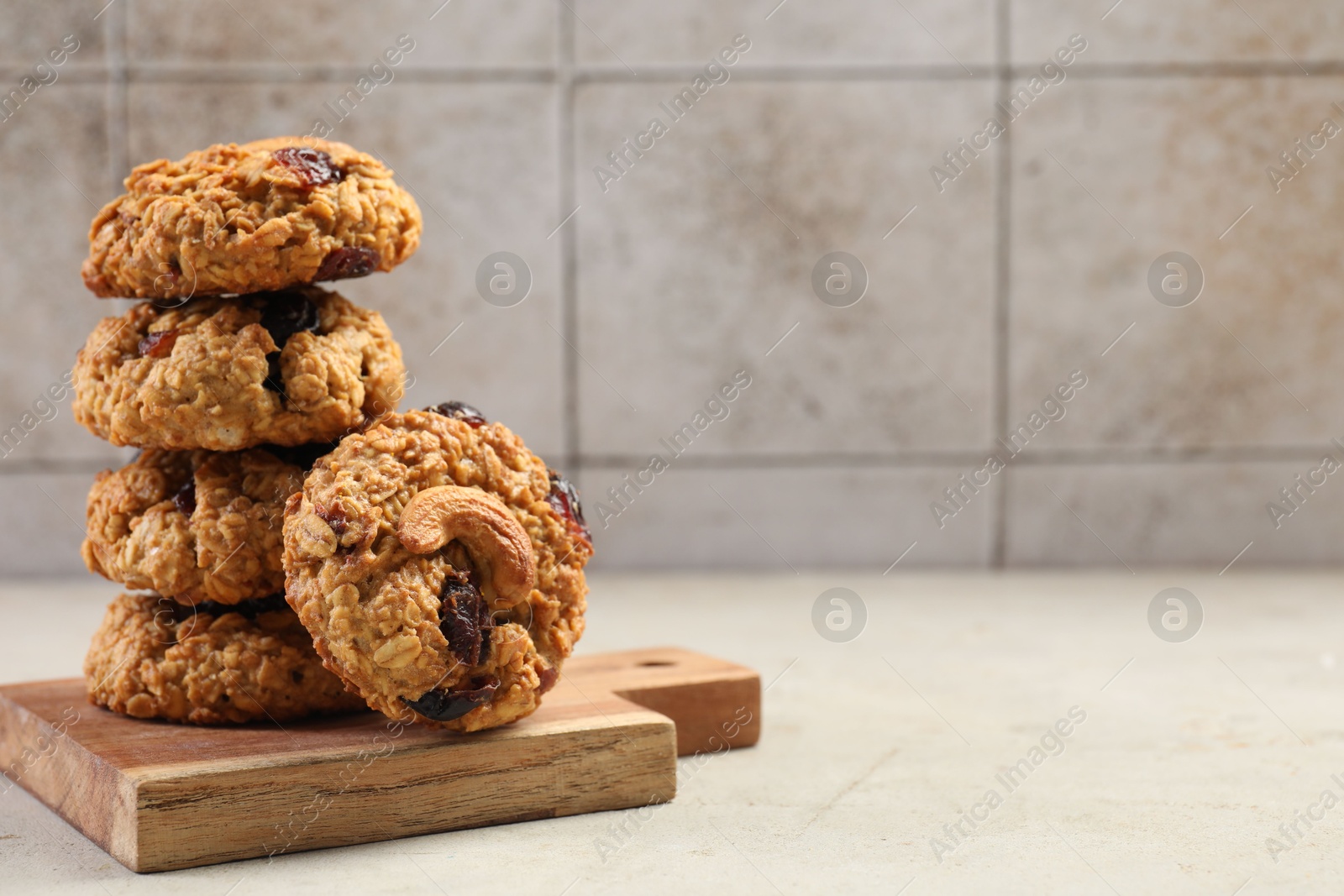 Photo of Delicious oatmeal cookies with raisins and nuts on light grey table, space for text