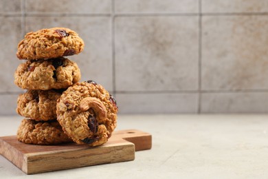 Delicious oatmeal cookies with raisins and nuts on light grey table, space for text