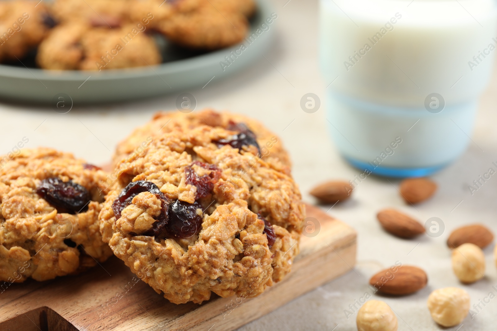 Photo of Delicious oatmeal cookies with raisins and nuts on light grey table, closeup