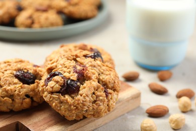 Delicious oatmeal cookies with raisins and nuts on light grey table, closeup