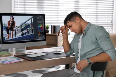 Photo of Tired retoucher at workplace with computer in office