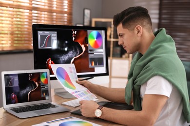 Professional retoucher with color palettes at workplace in office