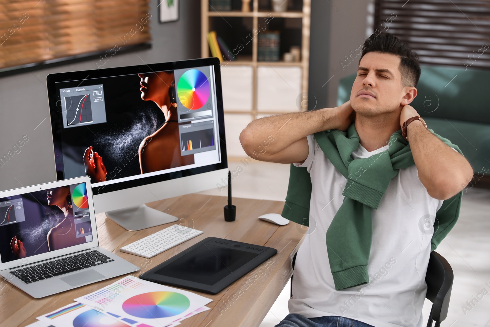 Photo of Tired retoucher at workplace with computer and laptop in office