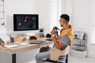 Photo of Professional retoucher working on graphic tablet at desk in office