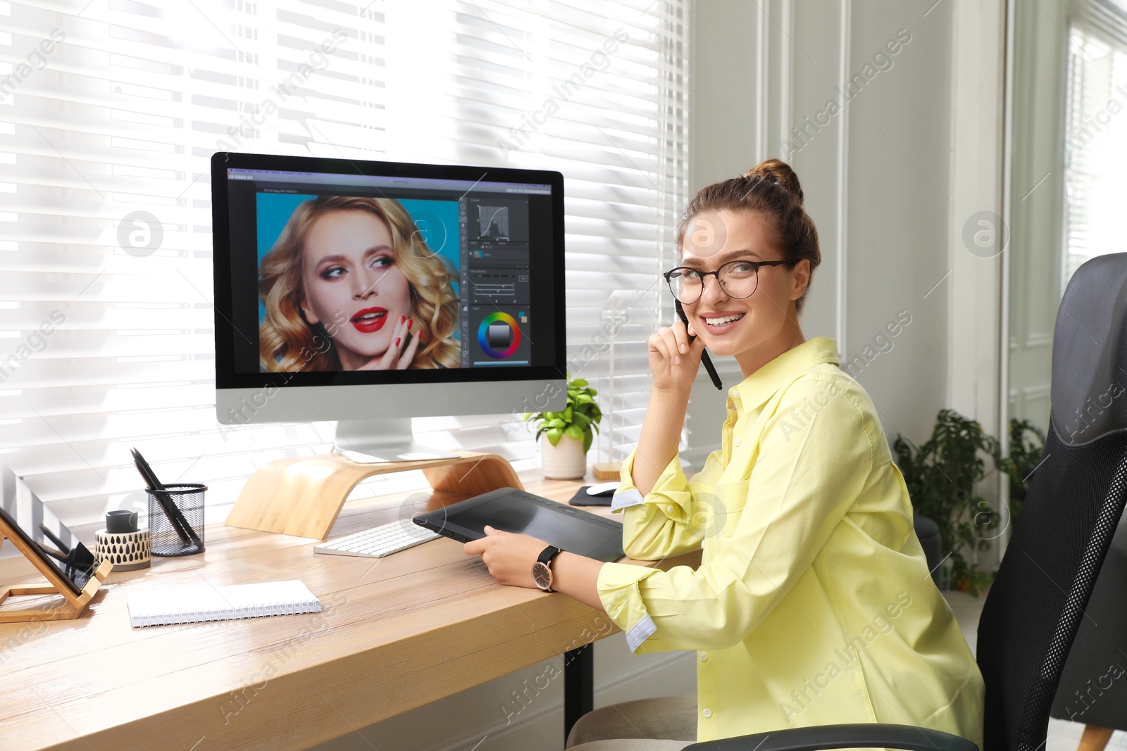 Photo of Professional retoucher working on graphic tablet at desk in office