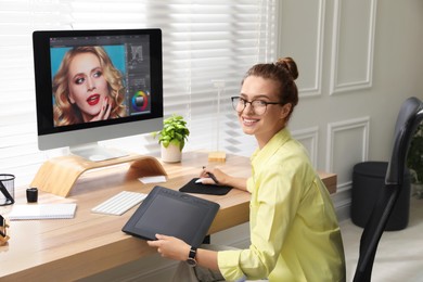 Professional retoucher working on graphic tablet at desk in office