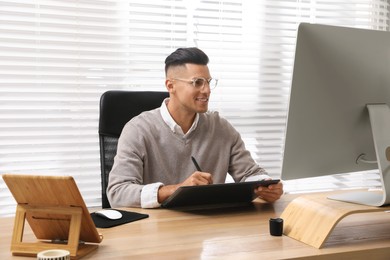 Photo of Professional retoucher working on graphic tablet at desk in office