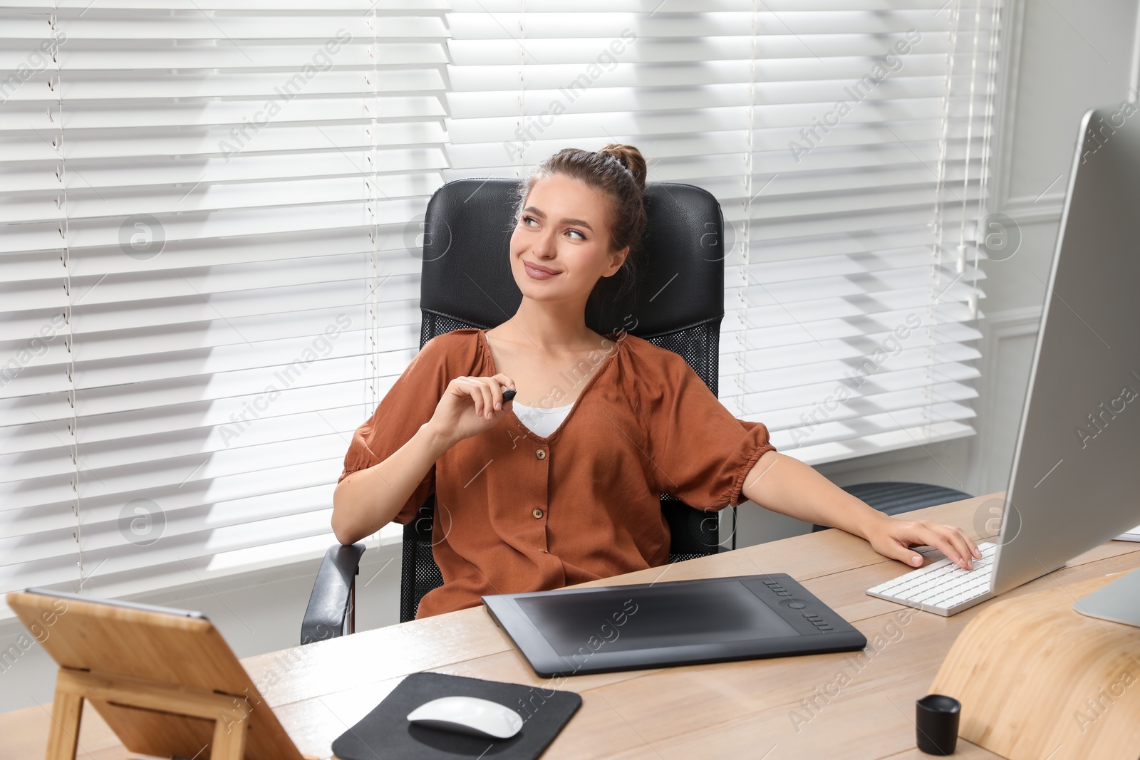 Photo of Professional retoucher working on graphic tablet at desk in office