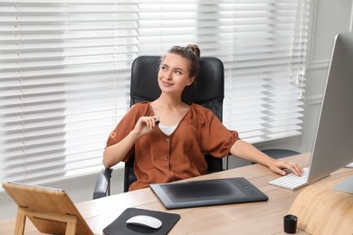 Photo of Professional retoucher working on graphic tablet at desk in office