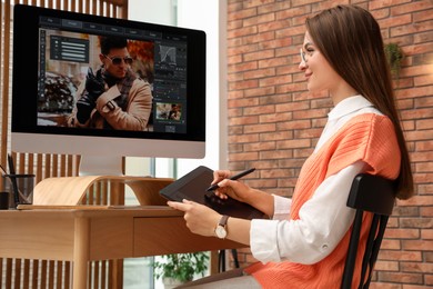 Photo of Professional retoucher working on graphic tablet at desk in office