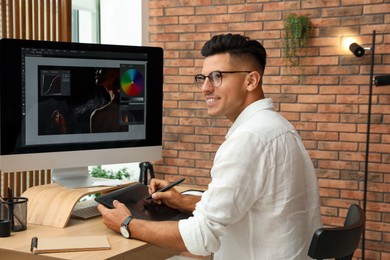 Photo of Professional retoucher working on graphic tablet at desk in office