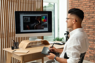 Photo of Professional retoucher working on graphic tablet at desk in office