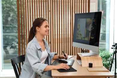 Photo of Professional retoucher working on graphic tablet at desk in office