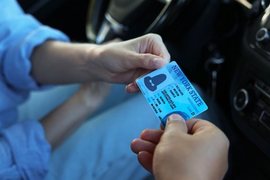 Photo of Driving school. Examiner giving driving license to student after exam in car, closeup