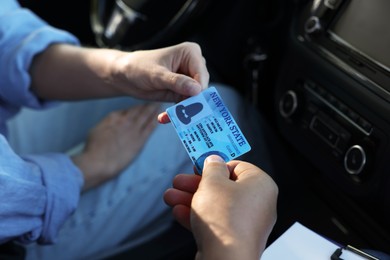 Photo of Driving school. Examiner giving driving license to student after exam in car, closeup