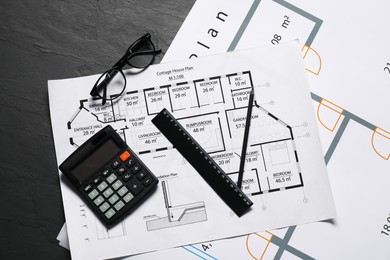 Different architectural drawings, glasses, calculator and ruler on grey textured table, flat lay