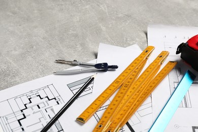 Photo of Different architectural drawings and tools on grey textured table