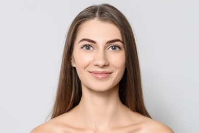 Photo of Beautiful young woman after henna eyebrows dyeing on light background