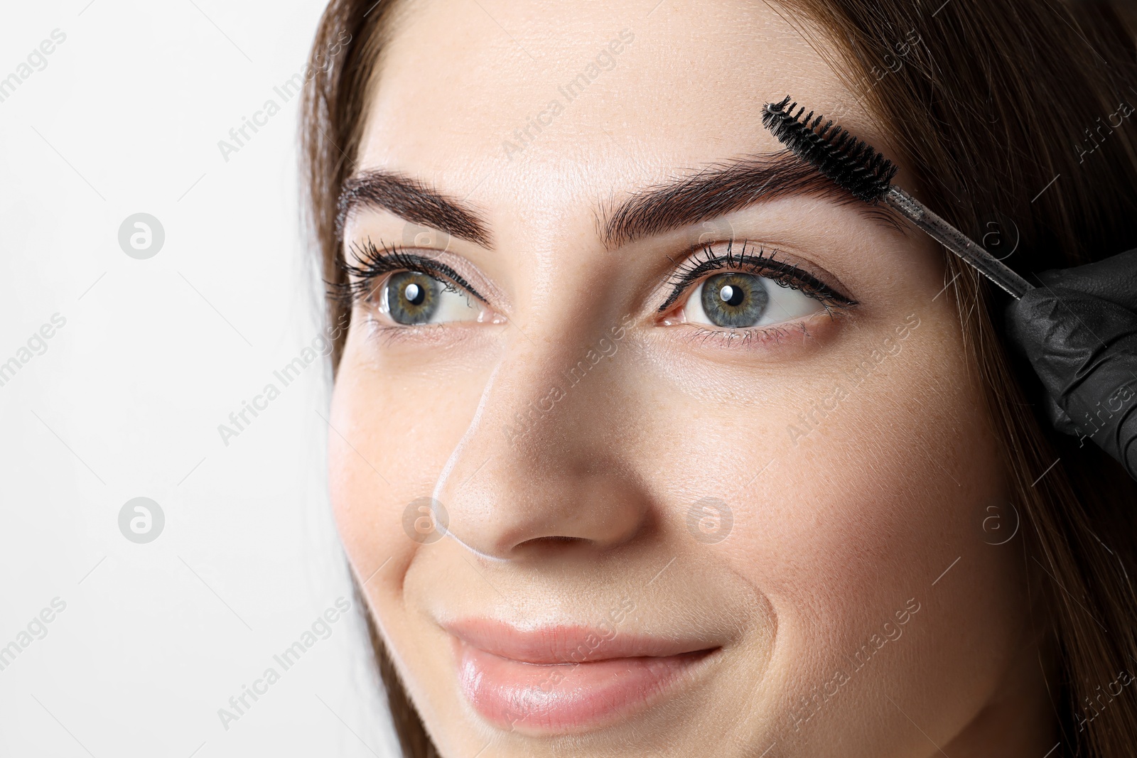 Photo of Beautiful young woman after henna eyebrows dyeing on light background, closeup