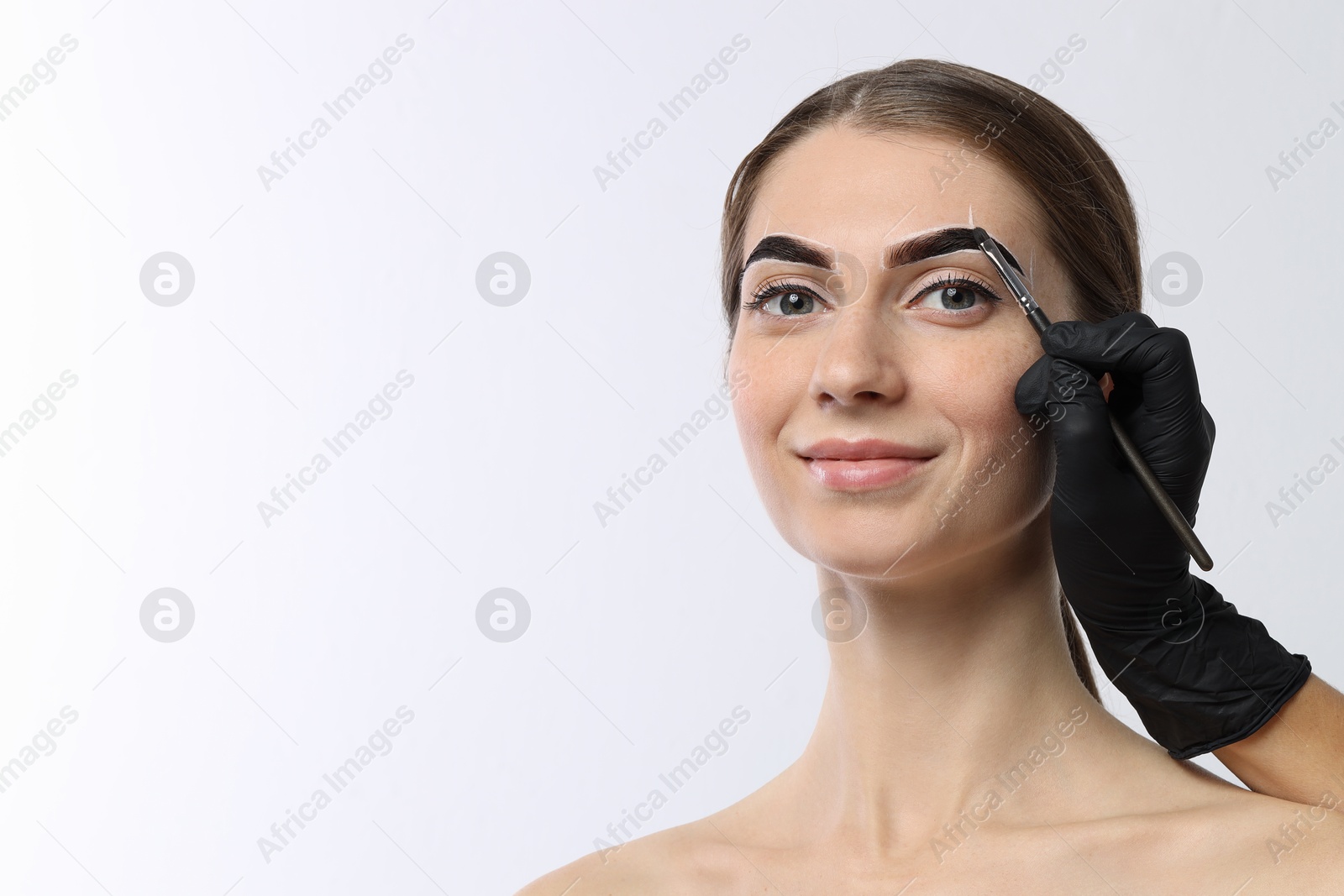 Photo of Young woman undergoing henna eyebrows dyeing on white background, closeup. Space for text