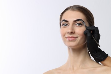 Photo of Young woman undergoing henna eyebrows dyeing on white background, closeup. Space for text