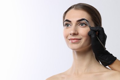 Photo of Young woman undergoing henna eyebrows dyeing on light background, closeup. Space for text