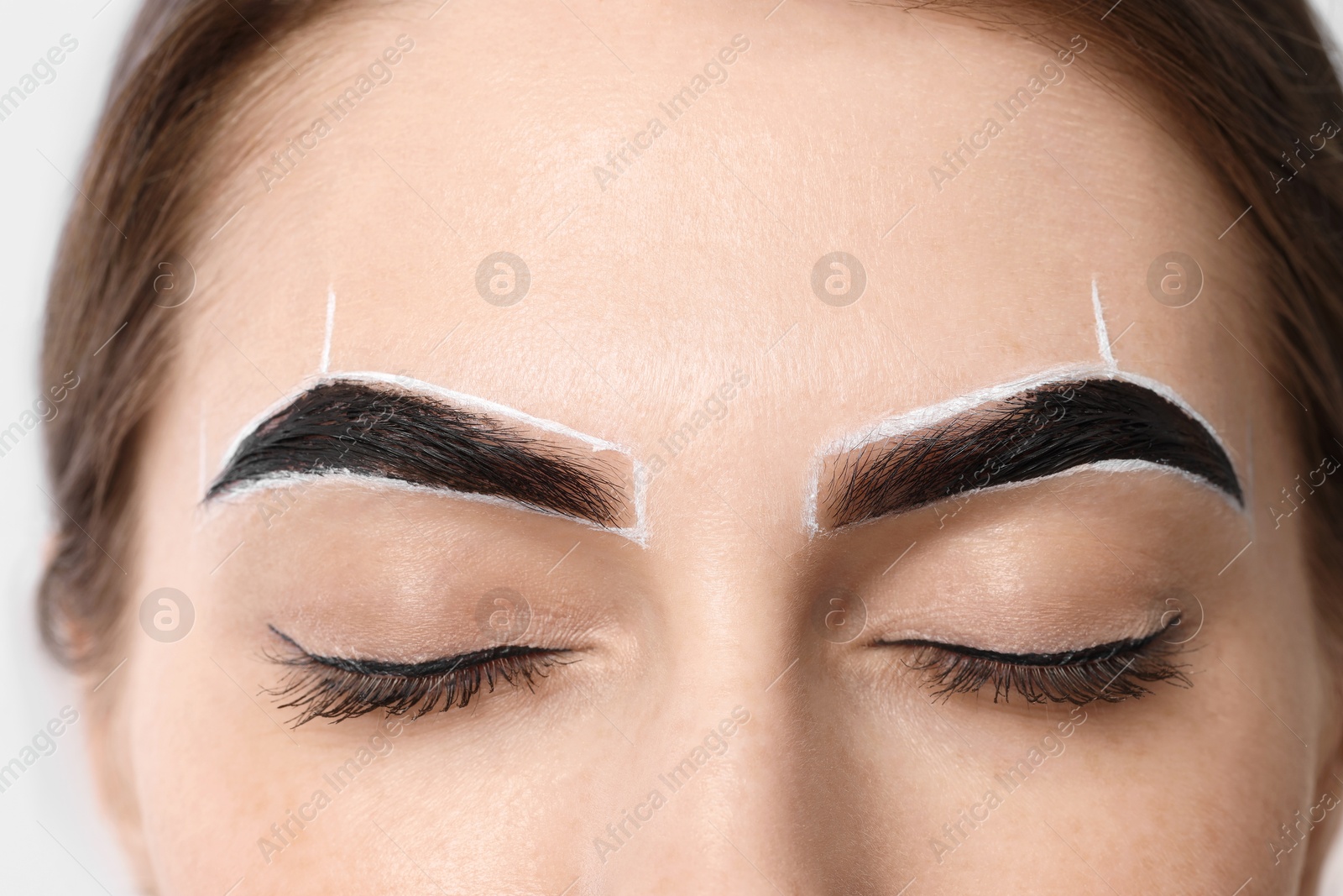 Photo of Young woman during henna eyebrows dyeing procedure, closeup