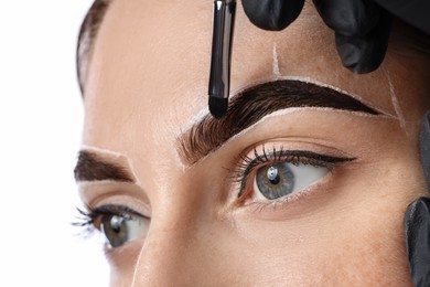 Photo of Young woman undergoing henna eyebrows dyeing on light background, closeup