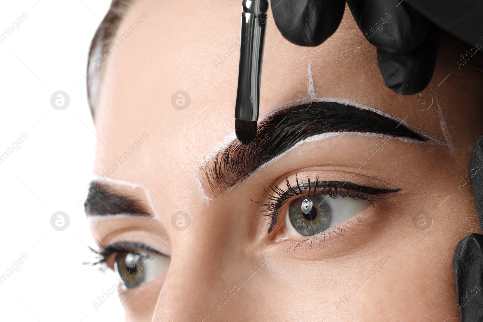 Photo of Young woman undergoing henna eyebrows dyeing on light background, closeup