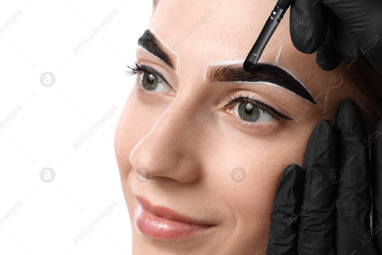 Photo of Young woman undergoing henna eyebrows dyeing on white background, closeup