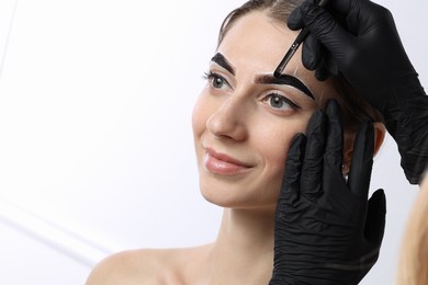 Photo of Young woman undergoing henna eyebrows dyeing on white background, closeup. Space for text