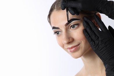 Photo of Young woman undergoing henna eyebrows dyeing on white background, closeup. Space for text