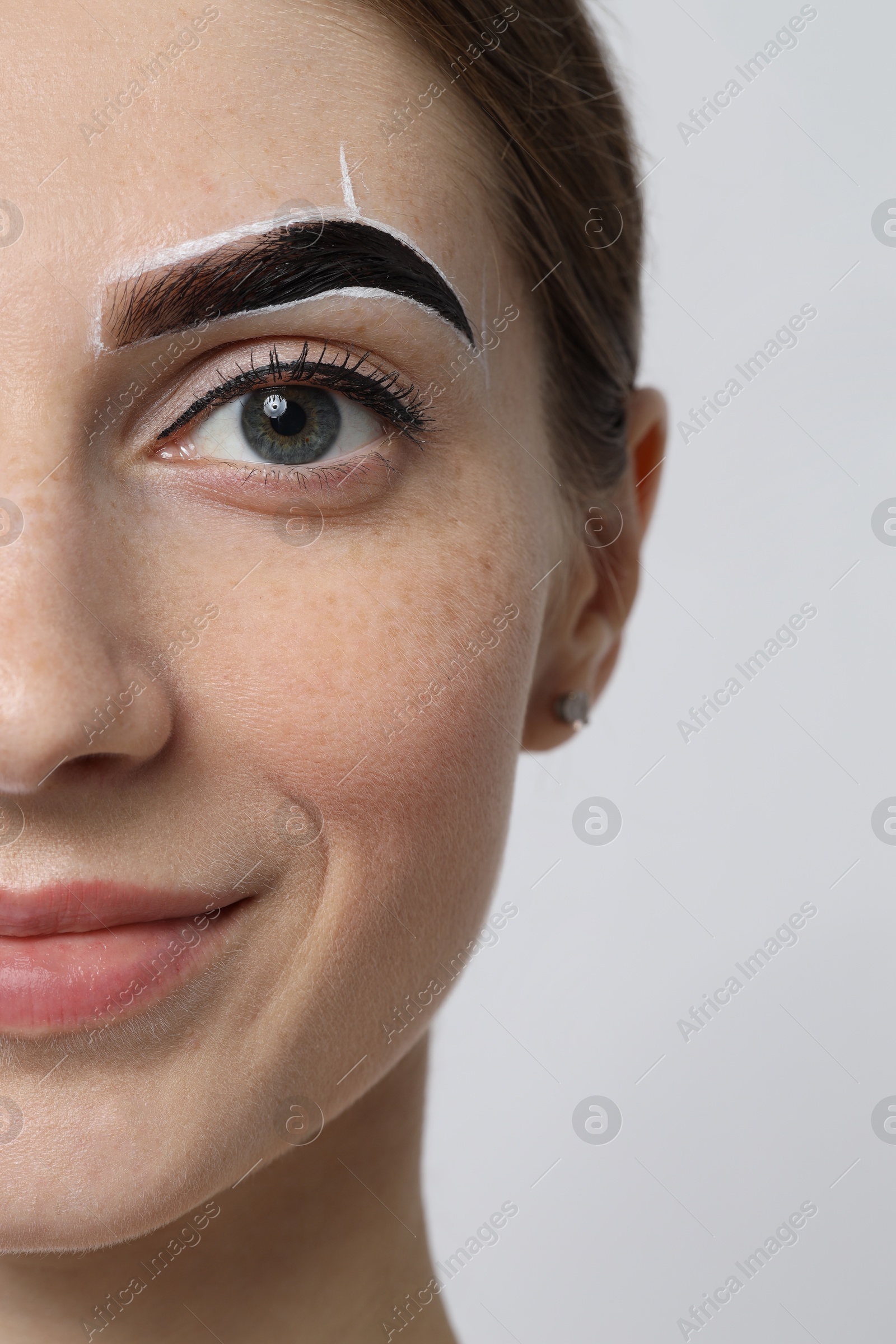 Photo of Young woman during henna eyebrows dyeing procedure on light background, closeup