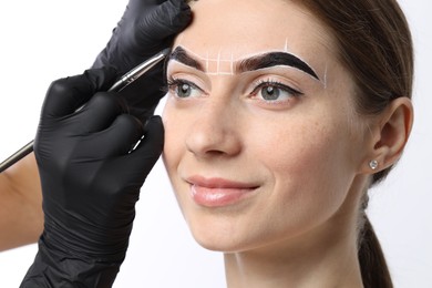 Photo of Young woman undergoing henna eyebrows dyeing procedure on white background, closeup