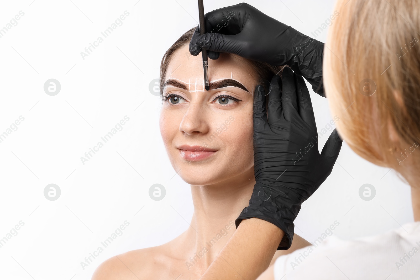 Photo of Young woman undergoing henna eyebrows dyeing procedure on white background