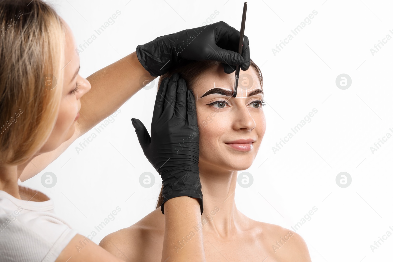 Photo of Young woman undergoing henna eyebrows dyeing procedure on white background