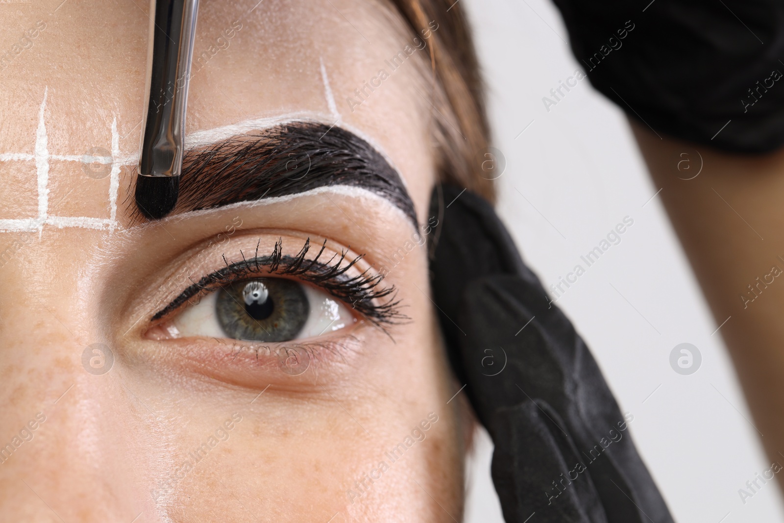 Photo of Young woman undergoing henna eyebrows dyeing procedure, closeup