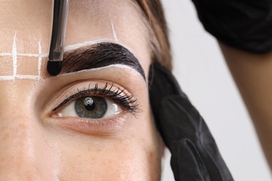 Young woman undergoing henna eyebrows dyeing procedure, closeup