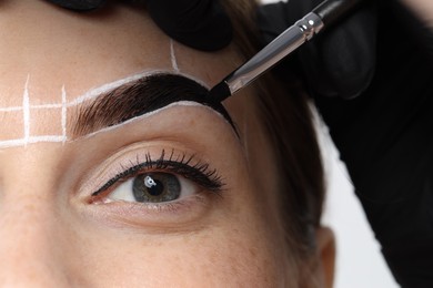 Photo of Young woman undergoing henna eyebrows dyeing procedure, closeup