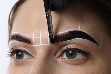 Young woman undergoing henna eyebrows dyeing procedure, closeup