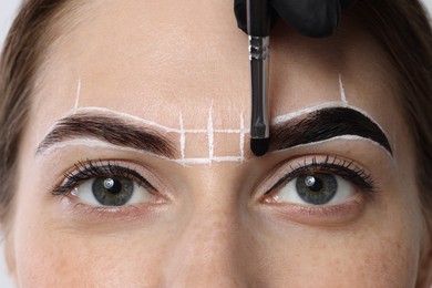 Photo of Young woman undergoing henna eyebrows dyeing procedure, closeup